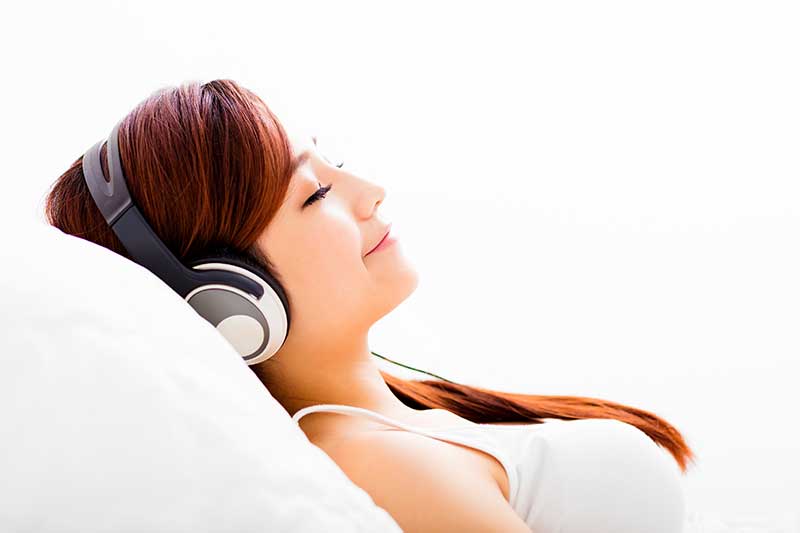 Young woman laying back and listening to music to ease her dental anxiety 
