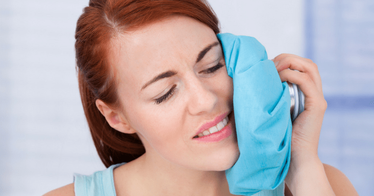 Woman holding an ice pack agains her left cheek
