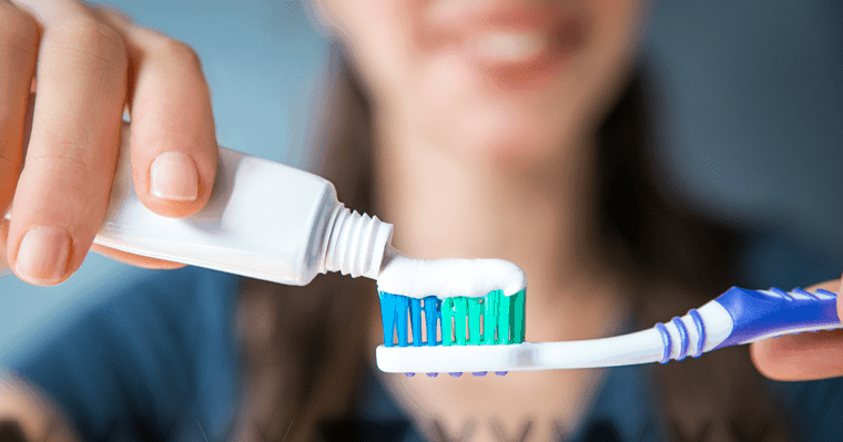 A woman putting toothpaste on her toothbrush